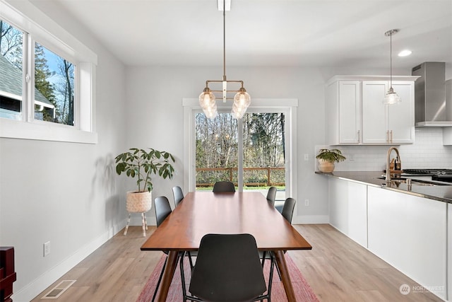 dining room with sink, a notable chandelier, and light wood-type flooring