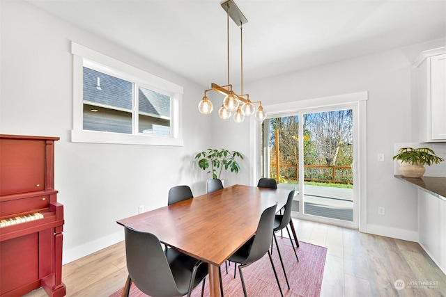 dining room with light wood-type flooring and a notable chandelier