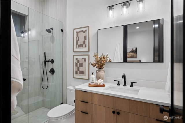 bathroom featuring vanity, toilet, and a shower with shower door