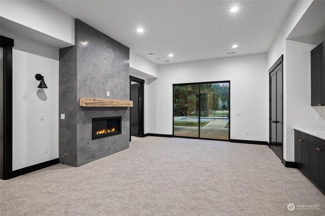 unfurnished living room featuring light colored carpet and a tile fireplace