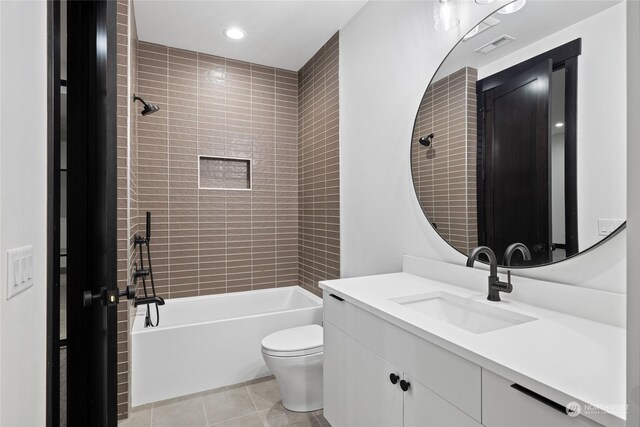 full bathroom with tile patterned floors, vanity, tiled shower / bath, and toilet