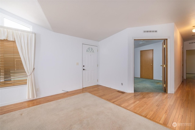 spare room featuring vaulted ceiling and hardwood / wood-style flooring