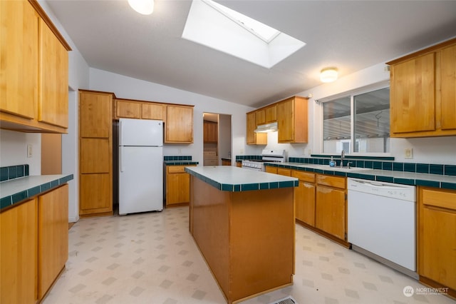 kitchen featuring a center island, white appliances, lofted ceiling with skylight, sink, and tile counters