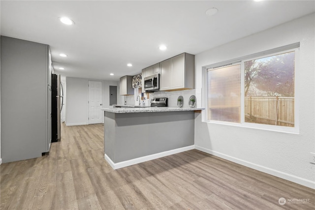 kitchen with gray cabinets, kitchen peninsula, light hardwood / wood-style flooring, and appliances with stainless steel finishes