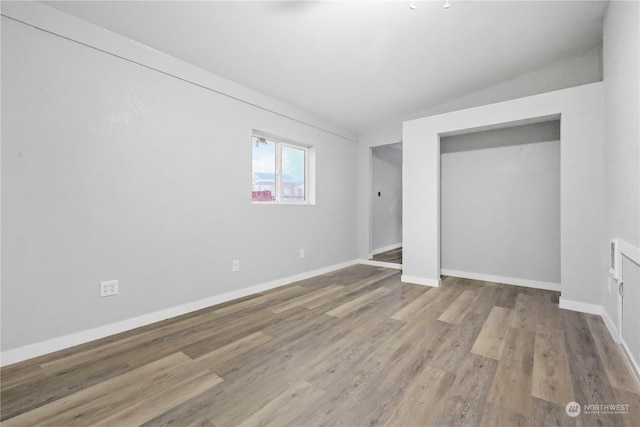 unfurnished room with vaulted ceiling and light wood-type flooring