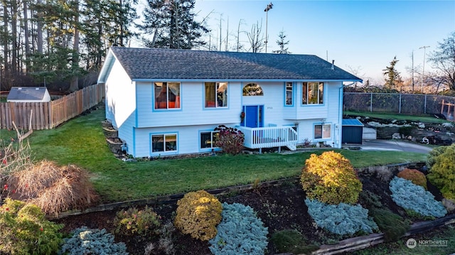 split foyer home with a storage unit, a deck, and a front lawn