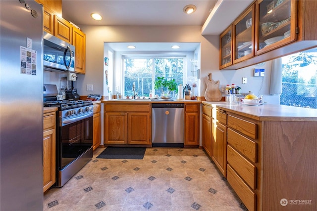 3945 Magrath Rd, Bellingham, WA 98226 - kitchen with appliances with stainless steel finishes, glass insert cabinets, brown cabinetry, recessed lighting, and a peninsula