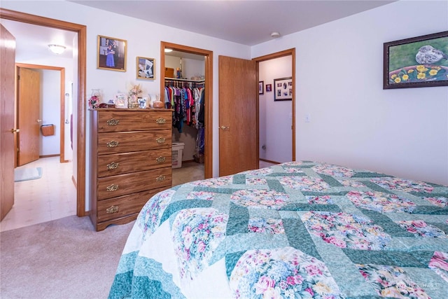 bedroom with a spacious closet, a closet, and light colored carpet