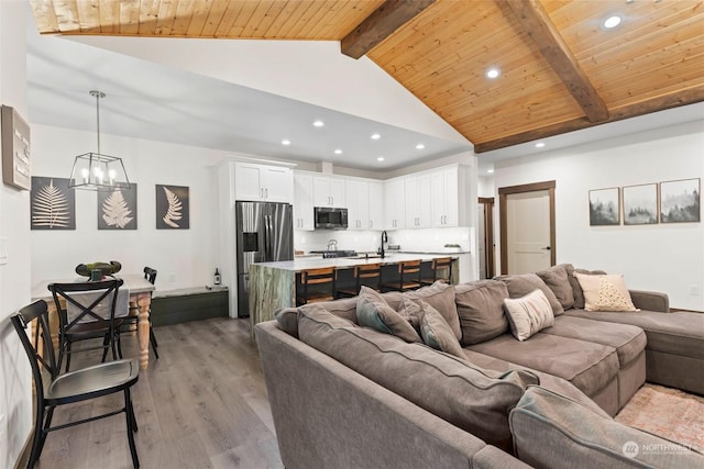 living room with high vaulted ceiling, wooden ceiling, beamed ceiling, hardwood / wood-style floors, and a chandelier