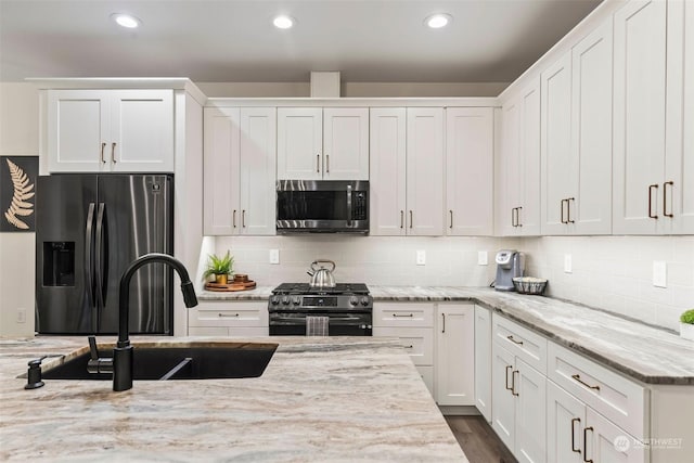 kitchen with white cabinets, appliances with stainless steel finishes, and light stone counters