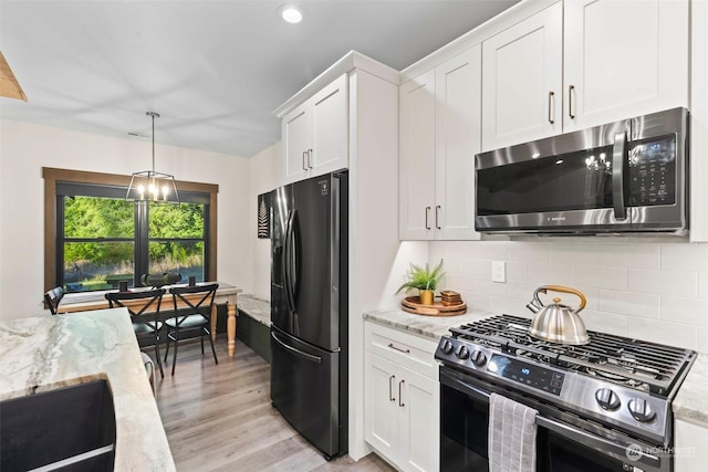 kitchen with white cabinets, light stone counters, light wood-type flooring, and stainless steel appliances