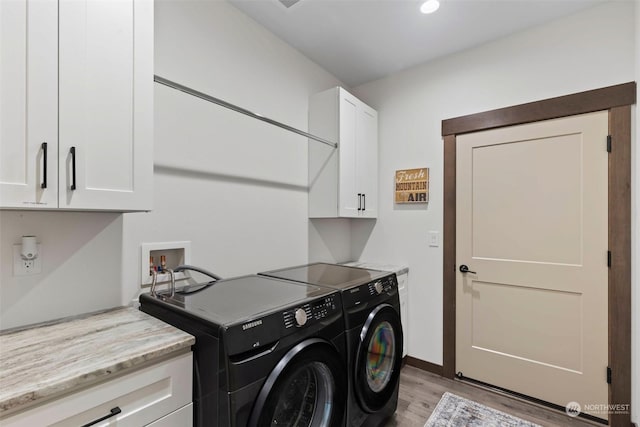 laundry area with cabinets, light wood-type flooring, and washing machine and dryer