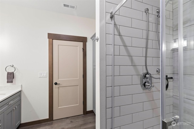 bathroom featuring hardwood / wood-style floors, vanity, and tiled shower