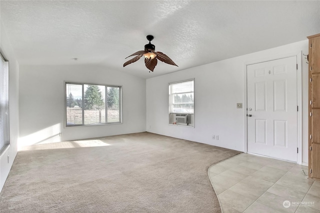 unfurnished room with a textured ceiling, light colored carpet, cooling unit, ceiling fan, and lofted ceiling