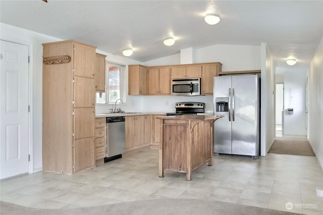 kitchen with light brown cabinets, sink, vaulted ceiling, appliances with stainless steel finishes, and a kitchen island