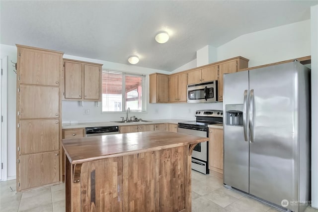 kitchen with appliances with stainless steel finishes, sink, a kitchen island, lofted ceiling, and light tile patterned flooring