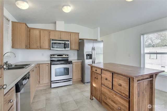 kitchen featuring a center island, lofted ceiling, sink, light tile patterned floors, and stainless steel appliances