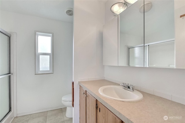 bathroom featuring toilet, vanity, tile patterned floors, and a shower with shower door