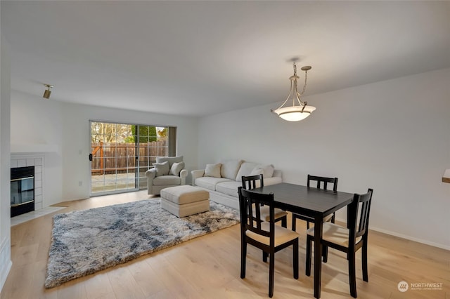 dining area with a tile fireplace and light hardwood / wood-style floors