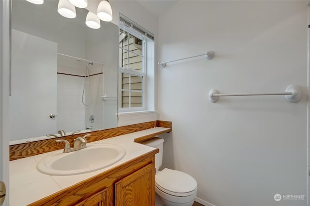 bathroom with tiled shower, vanity, and toilet