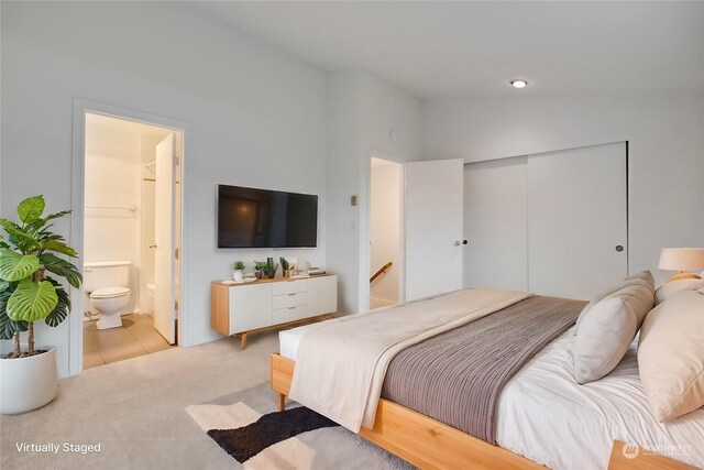 bedroom with lofted ceiling, light carpet, ensuite bath, and a closet