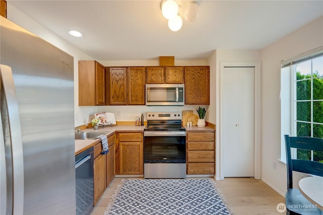 23953 58th Ct S Unit F3, Kent, WA 98032 - kitchen with appliances with stainless steel finishes, a sink, brown cabinetry, light wood-style floors, and light countertops
