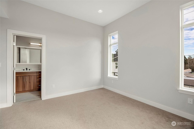 spare room featuring sink and light carpet