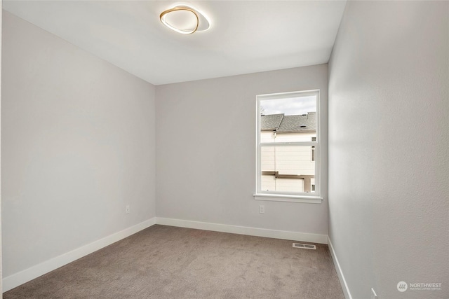 spare room featuring carpet floors, visible vents, and baseboards