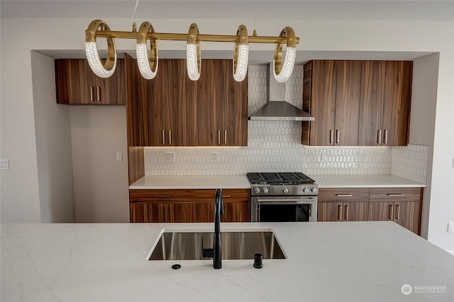 kitchen with tasteful backsplash, sink, stainless steel stove, and wall chimney range hood