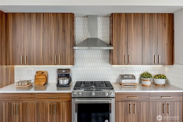 kitchen featuring stainless steel gas range, brown cabinetry, wall chimney range hood, and tasteful backsplash