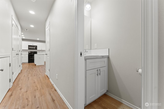 hallway with light wood-type flooring and sink