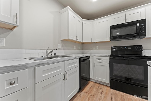 kitchen with black appliances, white cabinets, sink, light stone countertops, and light wood-type flooring