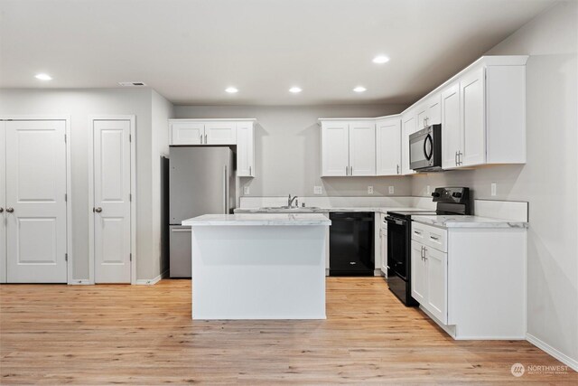 kitchen featuring light hardwood / wood-style flooring, white cabinetry, a kitchen island, and black appliances