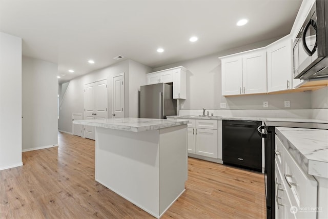 kitchen featuring white cabinets, a center island, light hardwood / wood-style floors, and black appliances