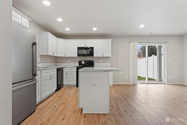 kitchen with black appliances, a center island, white cabinets, and light stone countertops