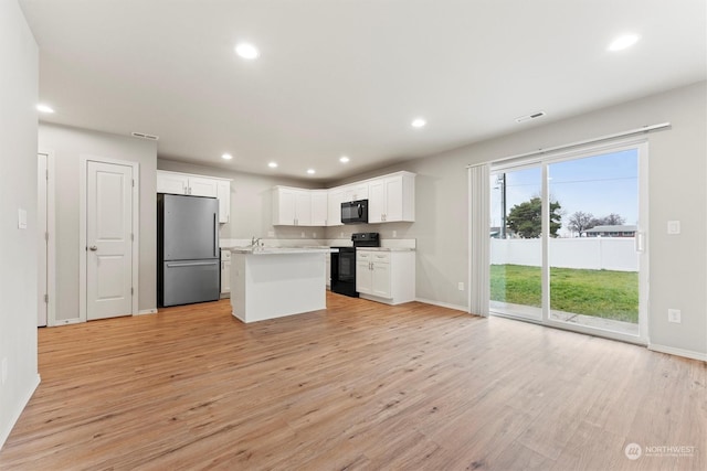 kitchen featuring white cabinets, light hardwood / wood-style flooring, a kitchen island, and black appliances