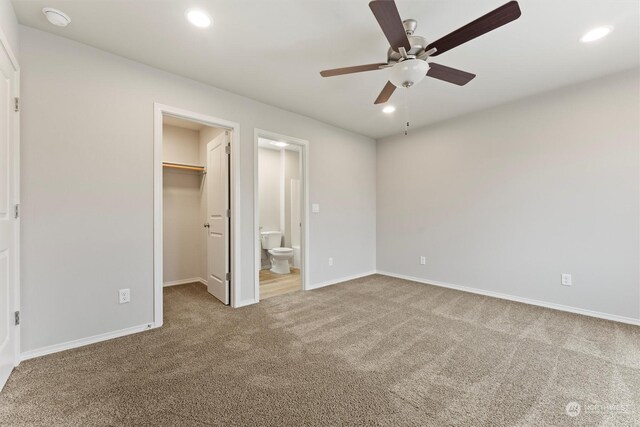 unfurnished bedroom featuring connected bathroom, ceiling fan, a walk in closet, a closet, and carpet