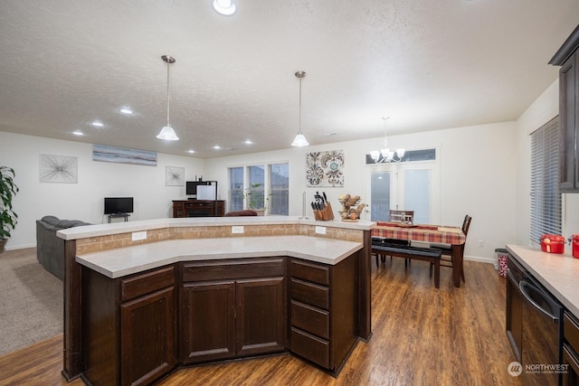 kitchen featuring dark wood-type flooring, hanging light fixtures, and a textured ceiling