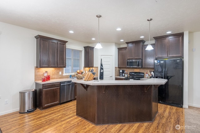 kitchen featuring pendant lighting, black appliances, and light hardwood / wood-style flooring