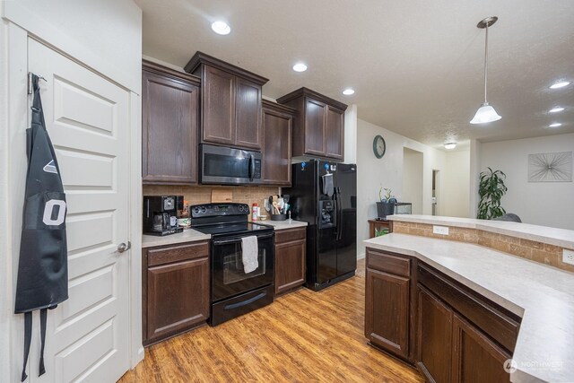 kitchen featuring tasteful backsplash, pendant lighting, dark brown cabinets, black appliances, and light wood-type flooring