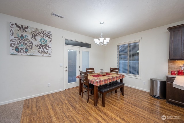 dining area featuring dark wood-type flooring and an inviting chandelier