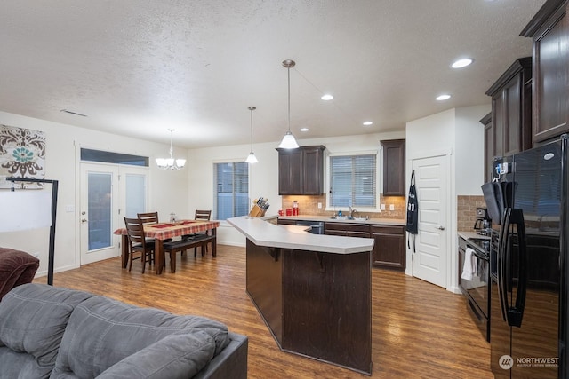 kitchen featuring dark hardwood / wood-style flooring, decorative light fixtures, tasteful backsplash, and black appliances