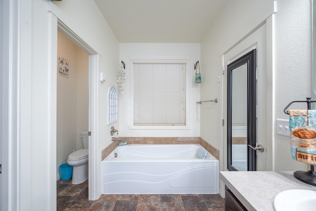 bathroom with a tub to relax in, vanity, and toilet