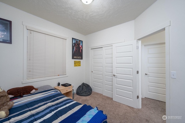 carpeted bedroom with a textured ceiling and a closet