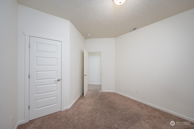 carpeted empty room with a textured ceiling