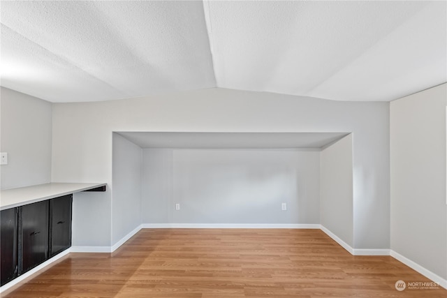 additional living space featuring lofted ceiling and light wood-type flooring