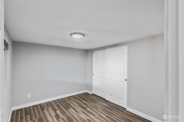 unfurnished bedroom with a closet and dark wood-type flooring