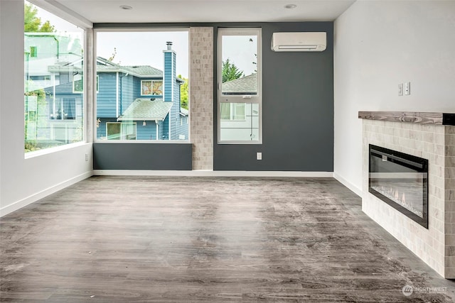 unfurnished living room featuring a wall mounted air conditioner, wood-type flooring, and a fireplace