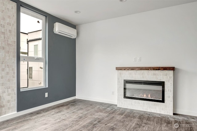 unfurnished living room with wood-type flooring, a fireplace, and a wall mounted AC