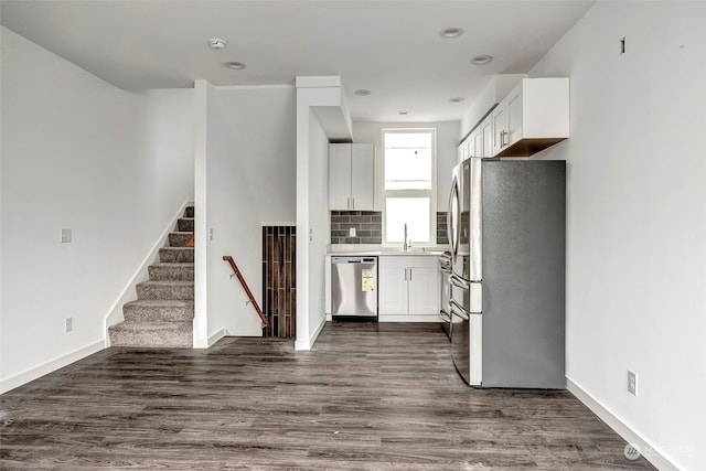 kitchen with dark hardwood / wood-style flooring, white cabinetry, backsplash, and appliances with stainless steel finishes